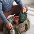 Person packing a Nura Wild Oil of Oregano pouch into a gym bag beside a water bottle